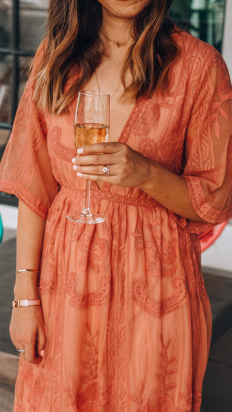 the lotus boutique blush lace dress holding champagne