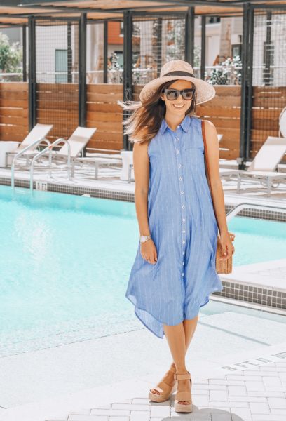 blue sleeveless button up dress with round rattan bag