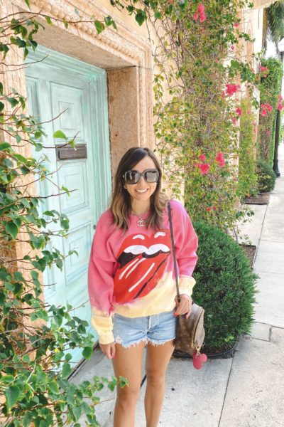 rolling stones tie dye sweatshirt with agolde shorts and louis vuitton palm springs