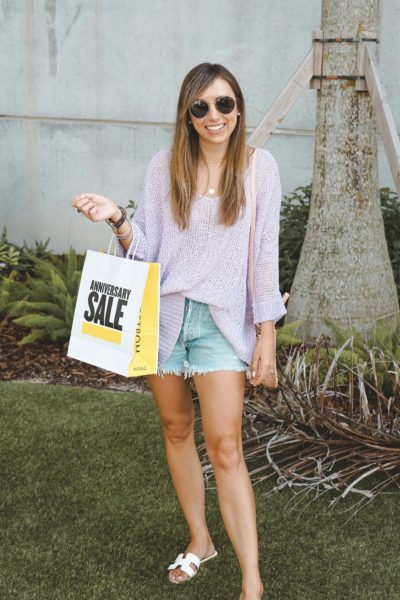 purple sweater with agolde shorts holding anniversary sale bag