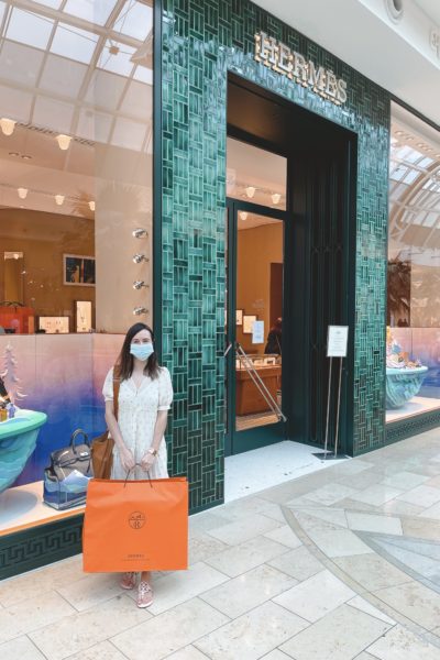 standing in front of hermes store with hermes bag