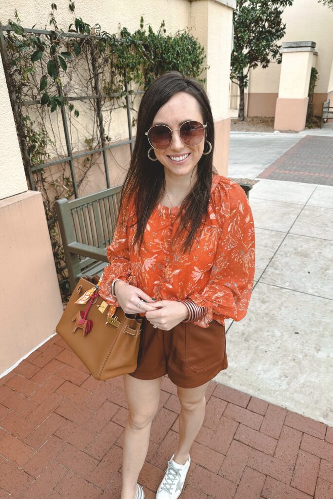 orange floral blouse with brown faux leather shorts and hermes birkin