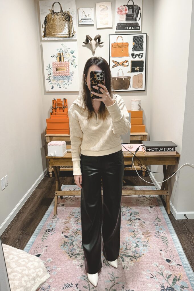 Black faux leather wide leg pants with quarter zip cream sweater and white booties