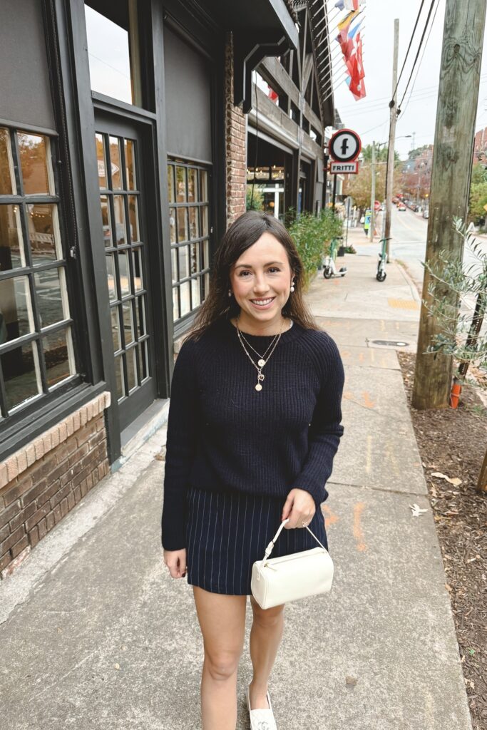 Navy cashmere sweater with navy pinstripe skort and the row 90s bag ivory